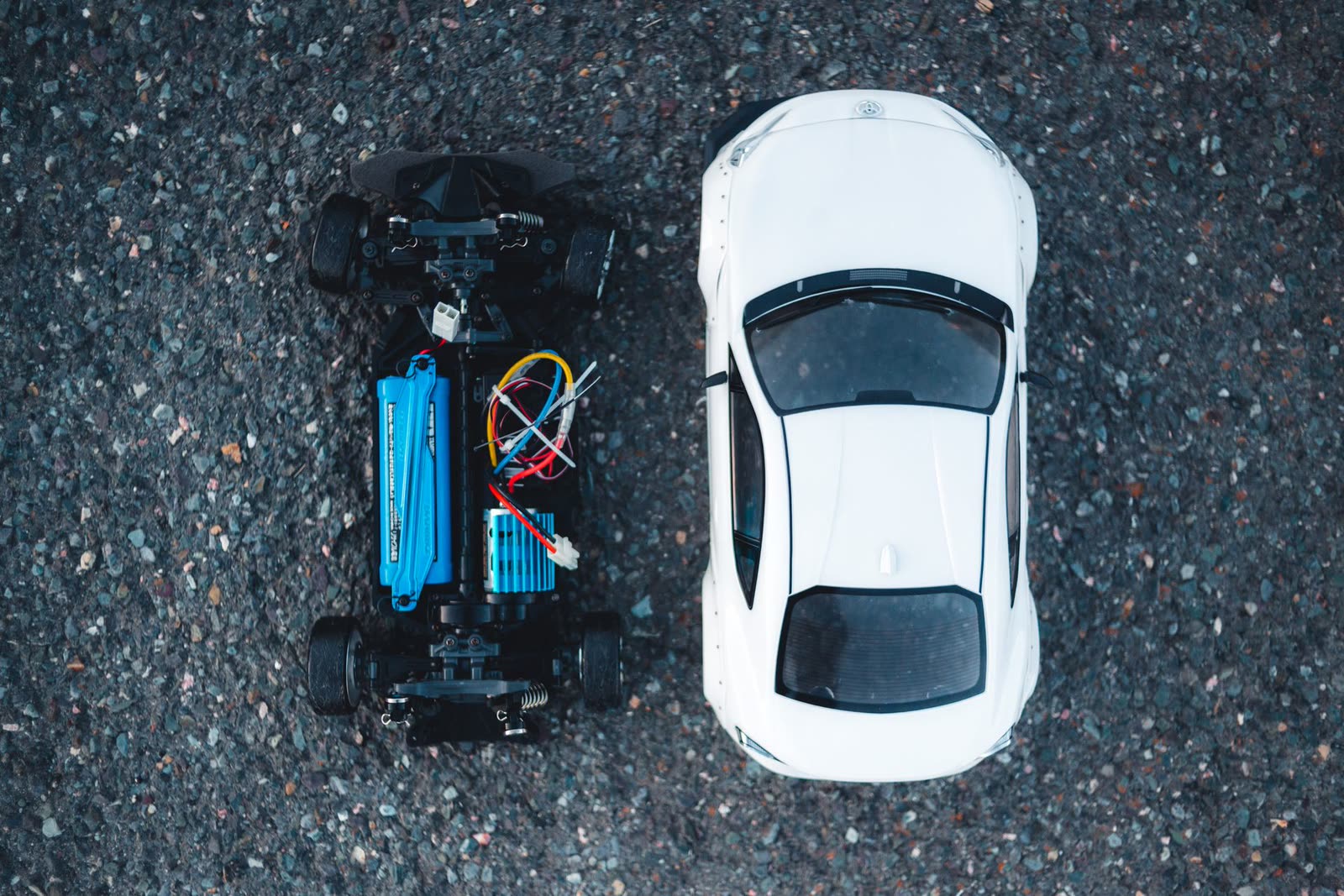 Hobby RC car chassis with its wiring exposed, beside its body shell