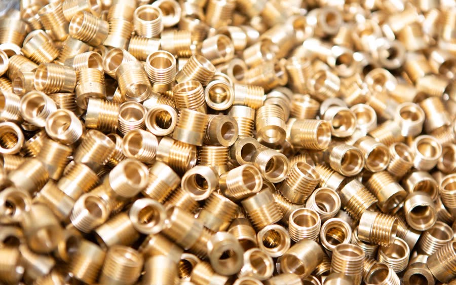 A pile of machined brass threaded inserts
